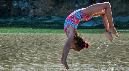 girl doing back flip into water