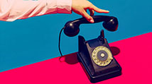 Arm in pink sleeve hanging up a black retro-style rotary phone